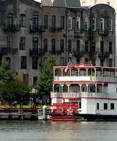 Paddle steamer on the river and old warehouses on River Street, Savannah, GA.